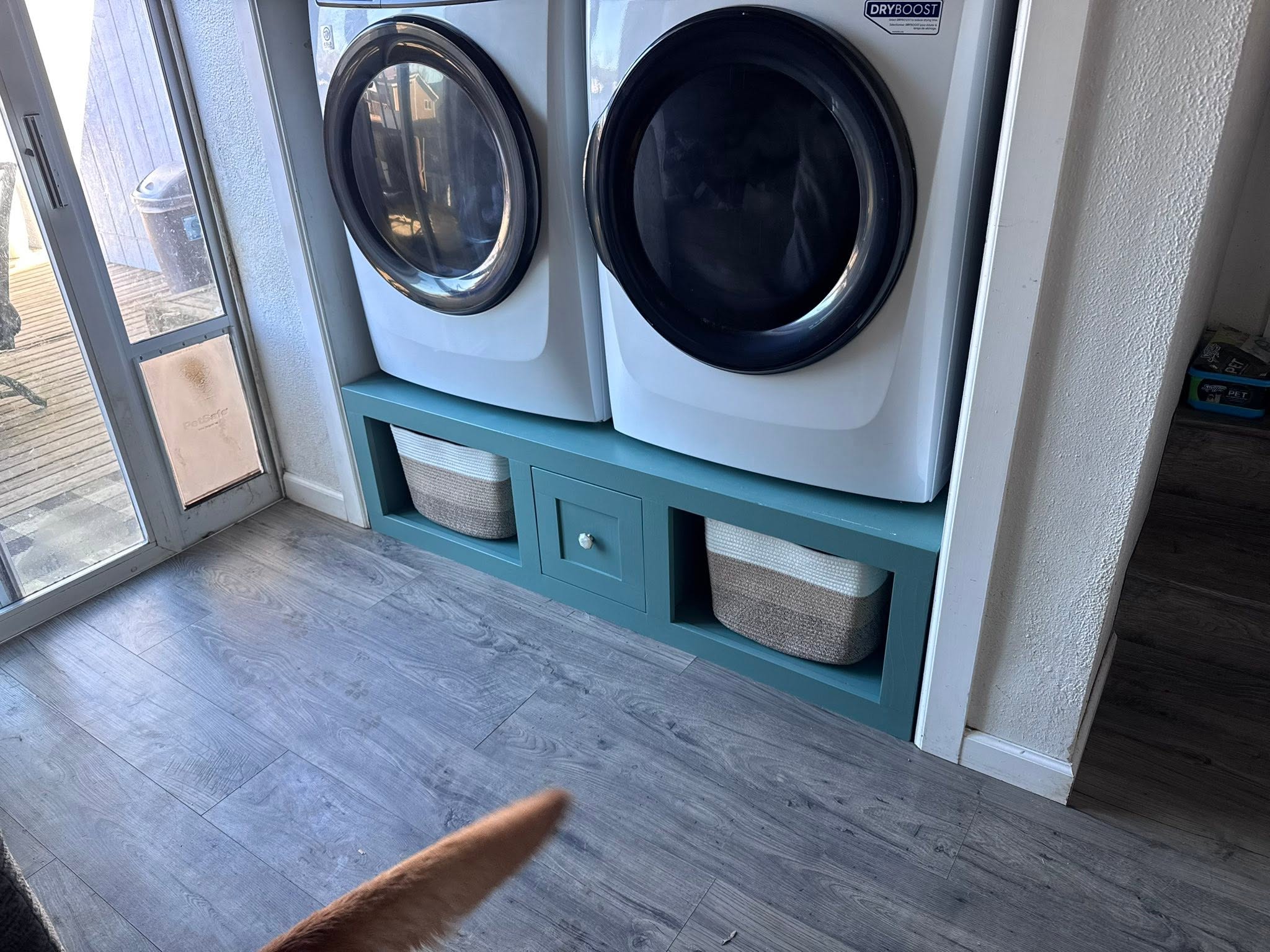 Custom teal laundry pedestal with storage built by JAM Home Services